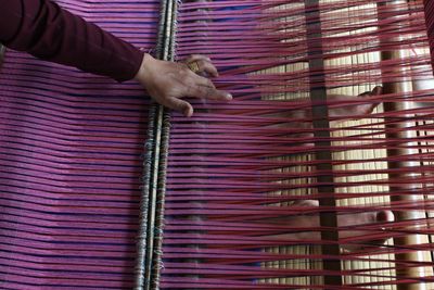 Low section of worker working on loom in textile factory