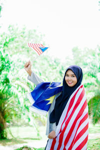 Muslim woman happy holding a malaysian flag. malaysia independence day.