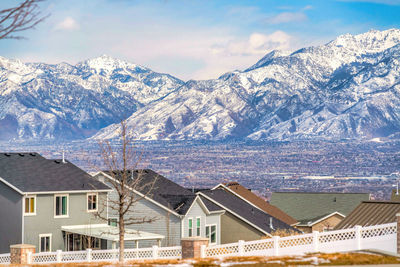 Houses by mountain against sky during winter