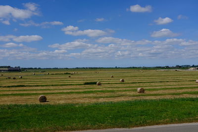 Hay bales on field against sky