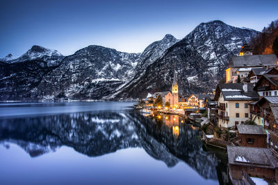 Reflection of buildings on snow covered mountain against sky