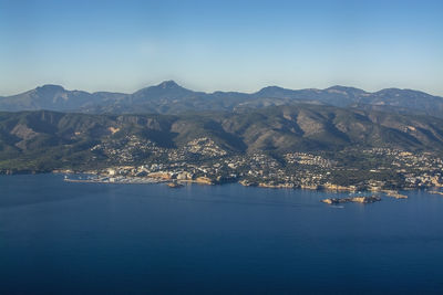 Aerial view of sea and mountains against clear blue sky