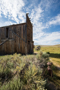 Abandoned wooden built structure in ghost town on field against sky