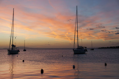 Sailboats in sea against sky during sunset