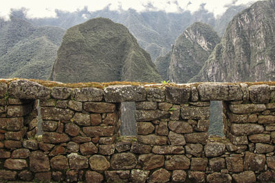 Stone wall by mountains against sky