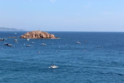 Boats in blue sea against sky on sunny day