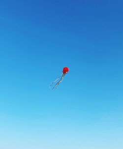 Low angle view of kite flying against clear blue sky