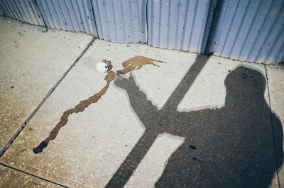 Optical illusion of shadow holding fallen disposable cup on sidewalk