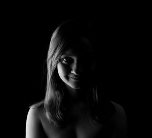 Close-up portrait of young woman against black background