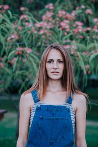 Young woman looking away while standing against plants at park