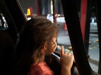Close-up of girl looking through window in car
