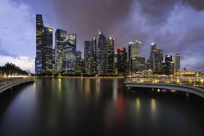 Illuminated buildings by lake in city at night