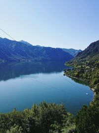 Scenic view of lake and mountains against clear blue sky