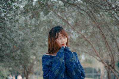 Portrait of woman standing against trees during winter