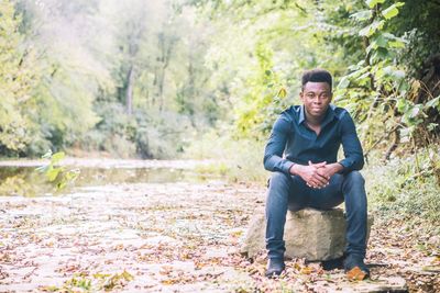 Full length of young man sitting in forest