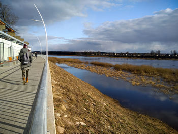 Man walking on lake against sky