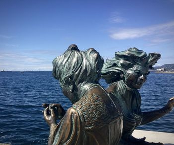 Statue by sea against blue sky