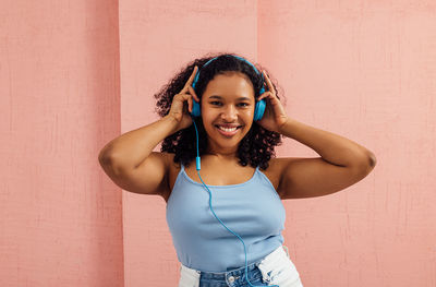 Portrait of young woman standing against wall