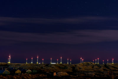 Illuminated factory against sky at night