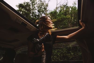 Low angle view of woman looking through sun roof