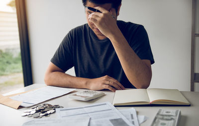 Man with head in hands calculating bills