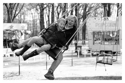 Smiling mother and son swinging at park