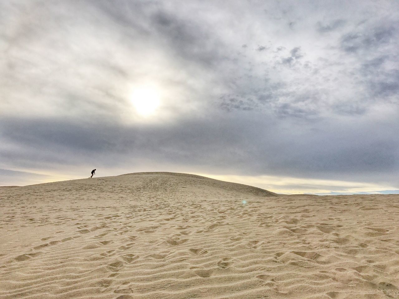 sand, desert, nature, cloud - sky, sky, sand dune, outdoors, one person, leisure activity, distant, beauty in nature, tranquility, full length, vacations, beach, day, scenics, landscape, arid climate, adults only, people, only men, adult, one man only