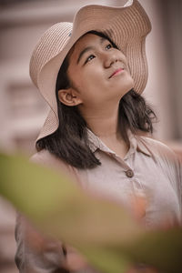 Close-up portrait of a young girl wearing a hat looking up to the sky 