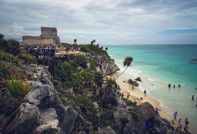 Group of people on beach by sea against sky