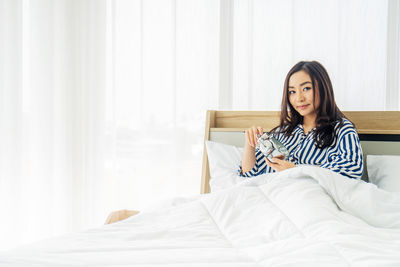 Portrait of woman sitting on bed in bedroom
