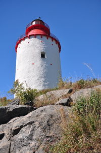 Low angle view of lighthouse by building against clear blue sky