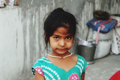 Close-up portrait of girl standing against wall