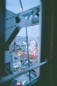 Illuminated ferris wheel by building in city