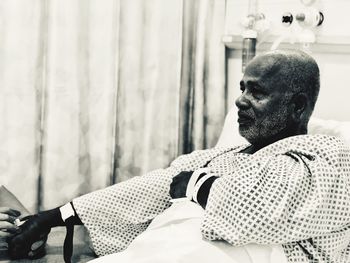 Thoughtful senior man sitting on bed in hospital