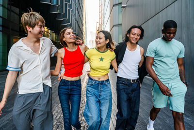 Portrait of smiling friends standing against wall