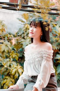 Thoughtful woman sitting against plants