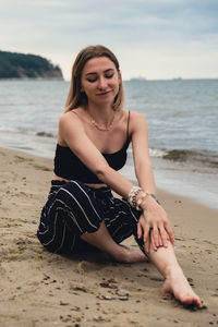 Young woman siting on blurred beachside background. attractive female enjoying the sea shore. travel