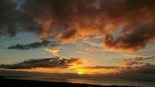 Scenic view of sea against dramatic sky during sunset