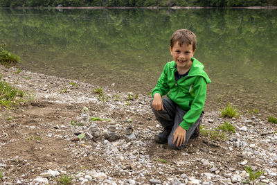 Portrait of boy kneeling at lakeshore