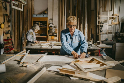 Senior craftswoman making frame at carpentry workshop