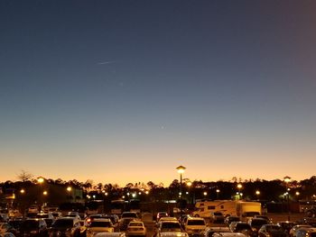 Cars on illuminated city against clear sky at night