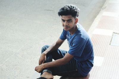 High angle view of young man sitting on footpath