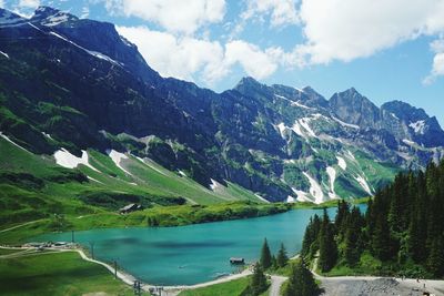 Scenic view of blue lake and rocky mountains against sky on sunny day