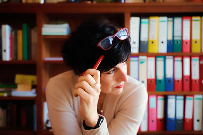 Woman sitting against book at office