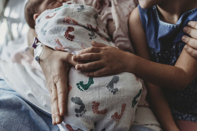 Close up detail of mother holding newborn son with sibling