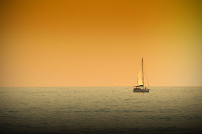 Sailboat sailing on sea against sky during sunset