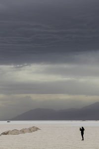 Silhouette man standing on beach against sky