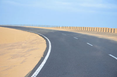 Empty road by land against sky