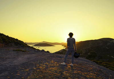 Rear view of man walking on mountain against clear sky