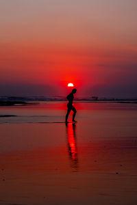 Silhouette person standing on beach during sunset